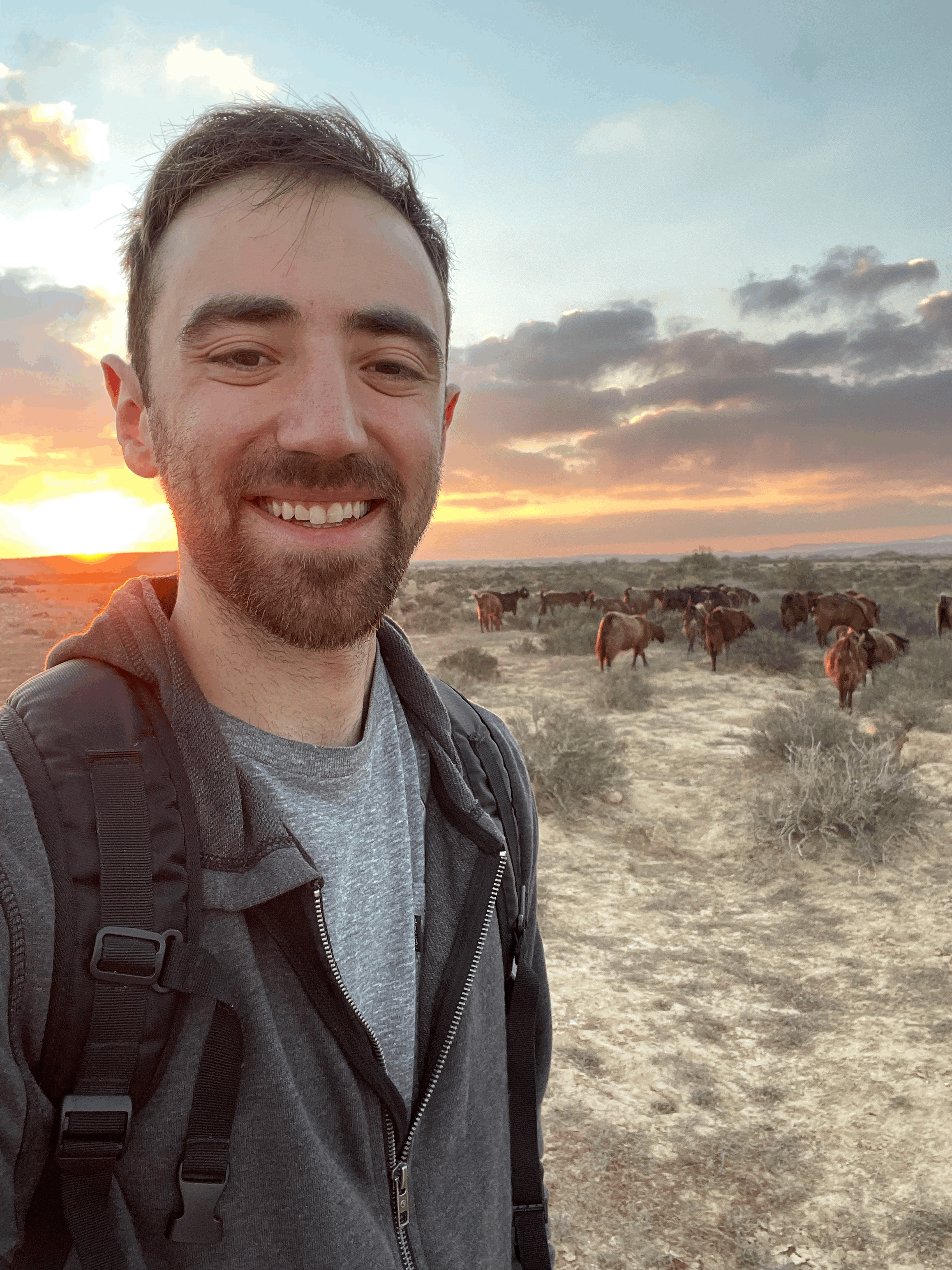 Jacob smiling in the desert at sunrise with 75 goats