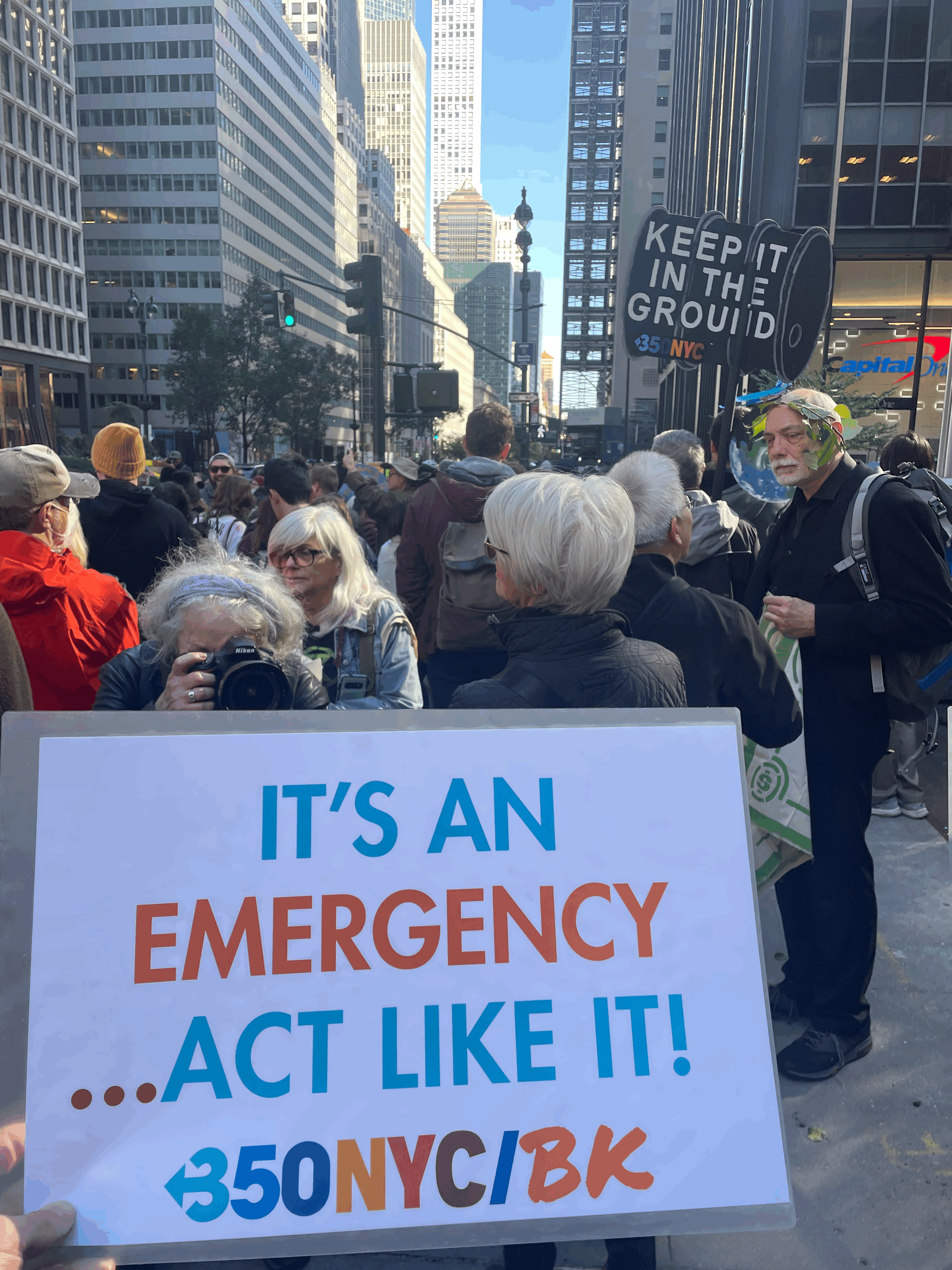 A group of environmental protestors gathered on Park Avenue, with a sign I'm holding that reads "it's an emergency... act like it!"