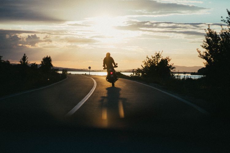 A motorcycle riding down a road at sunset