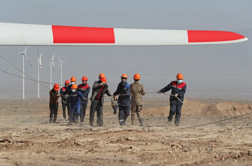 Workers pulling a rope under a windmill arm